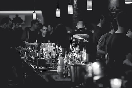 grayscale photo of group of people at the bar