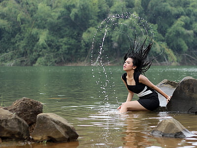 woman wearing black and white dress sitting near water