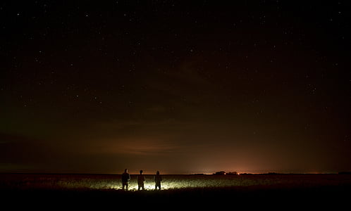 three people holding flashlight during night