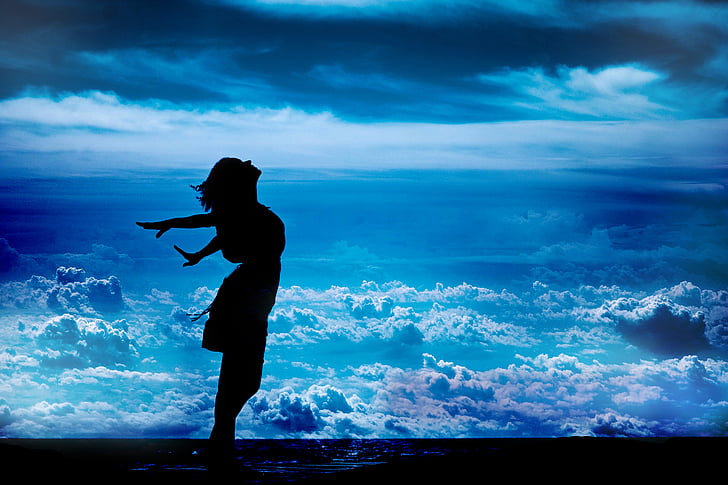 silhouette of standing woman while spreading her arms sideward