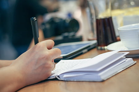 shallow focus photo of person writing on notebook