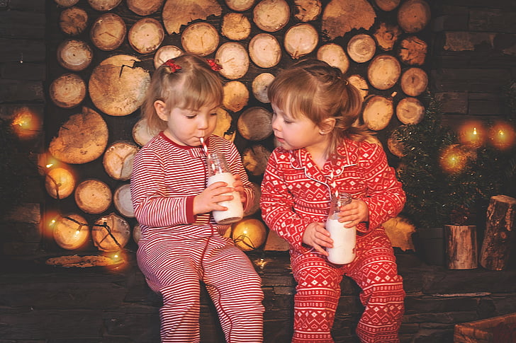 two girls wearing footie pajamas sipping drink