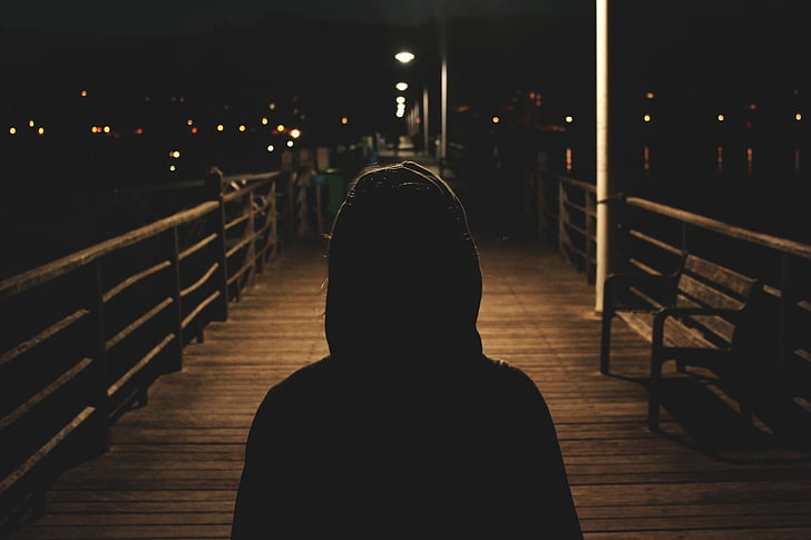 photo of person's silhouette standing on wooden ground