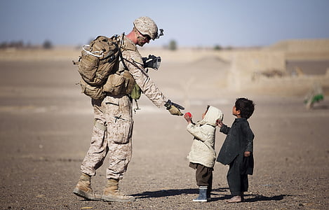 child giving a pink ball to a marine soldier
