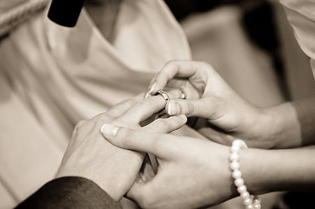 grayscale photography of person holding silver-colored wedding ring