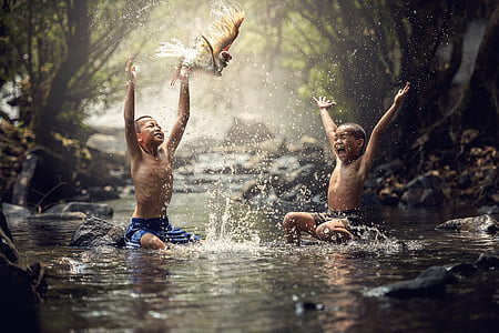 two topless boys taking a bath on streams at daytime