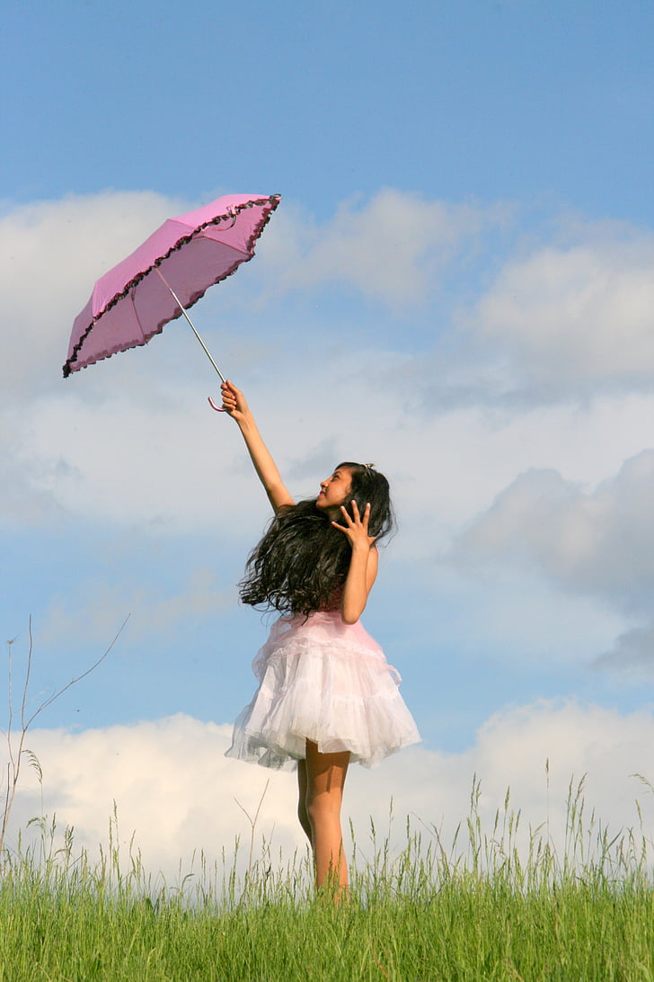 woman in pink and white sleeveless dress holding pink umbrella