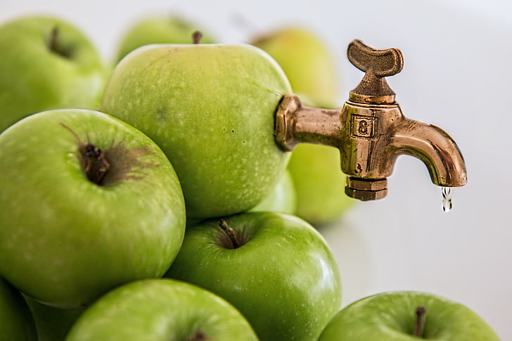 close-up photography of granny Smith apple with brass-colored faucet