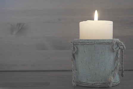 white pillar candle on gray wooden case
