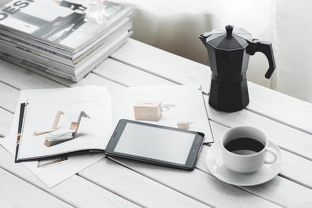 white ceramic teacup near black smartphone on table