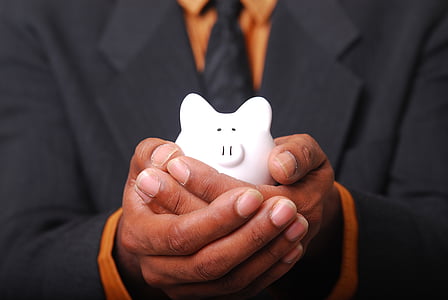 person holding white piggy bank