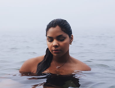 black hair woman standing in black body of water
