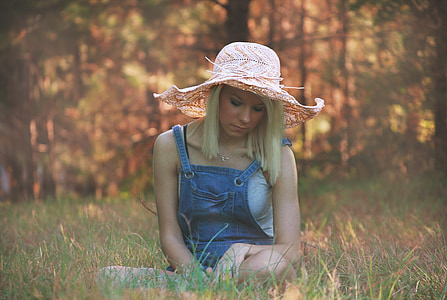 woman wearing pink beach hat sitting on green grass