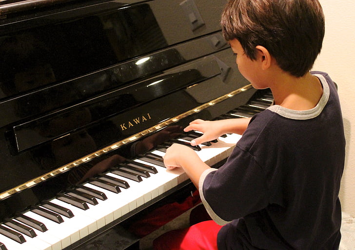boy wearing black shirt playing Kawai piano