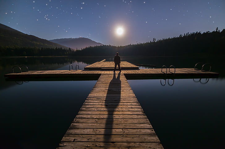 man standing on dock during night time