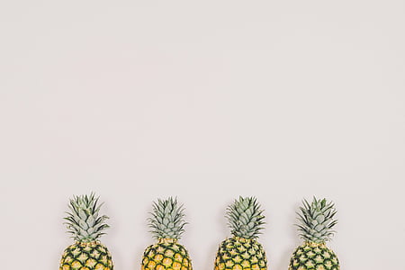 four pineapples on white wall