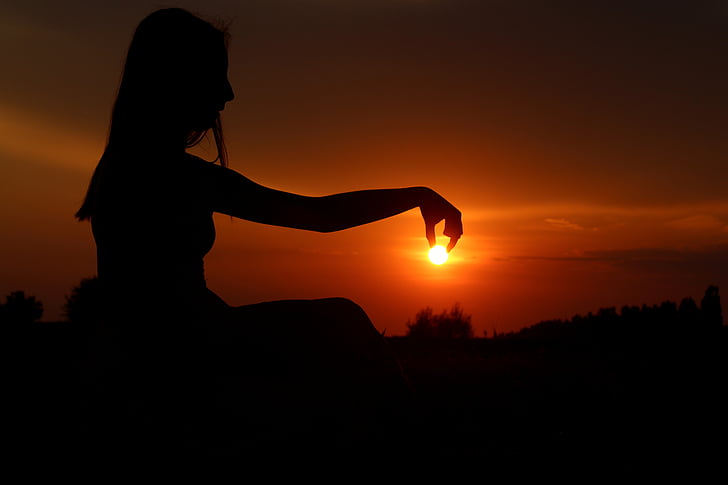silhouette of woman holding sun