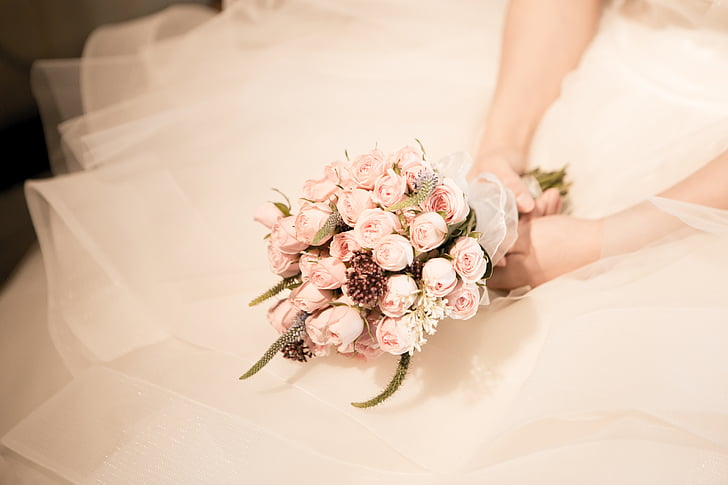 woman wearing wedding dress holding pink rose bouquet