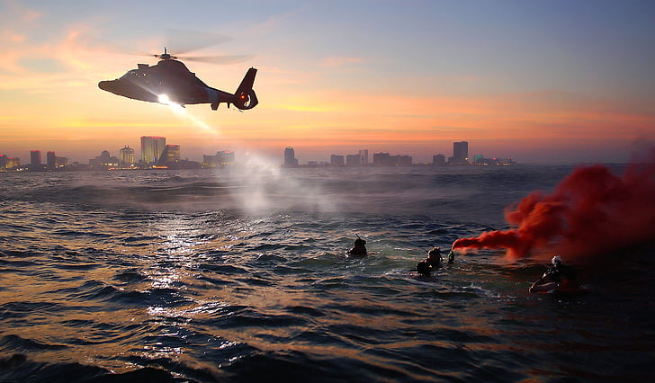 people on ocean with helicopter above them