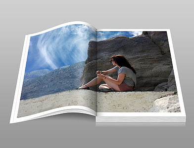 photo of open book page displaying woman sitting near brown rock during day time