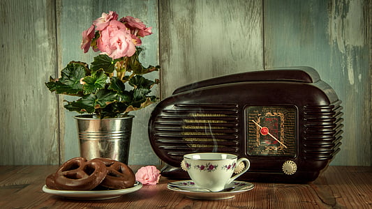 black vintage radio and white ceramic cup with saucer on brown surface