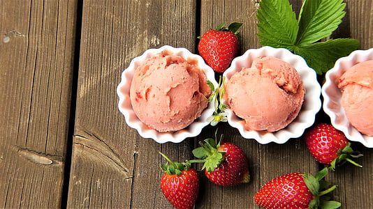 three strawberry ice cream and fruit on wooden surface