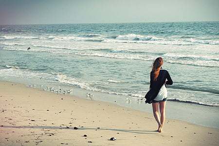 woman walking beside of beach during daytime