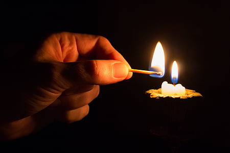 person lighted candle using match stick
