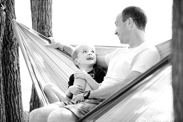 grayscale photograph of father and son in hammock
