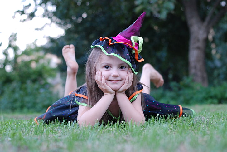 shallow focus photography of girl wearing black witch costume on grass field