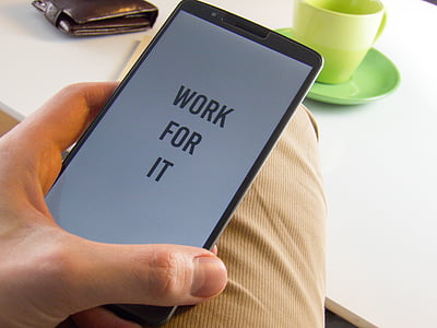 person holding smartphone flashing work for it text