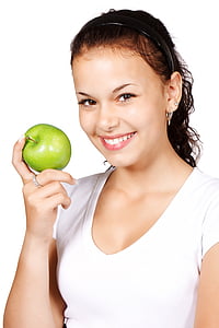 woman in white shirt holding green apple
