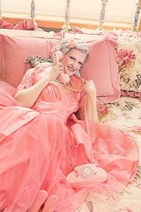 woman wearing pink dress holding pink telephone