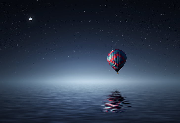 red and blue hot air balloon over body of water at night time