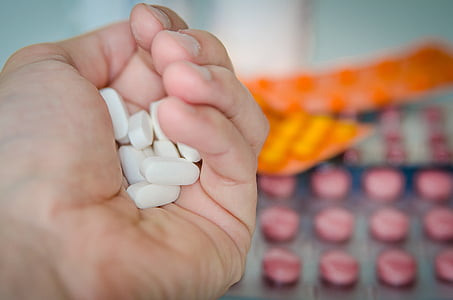 oblong white medication pills on person's hand