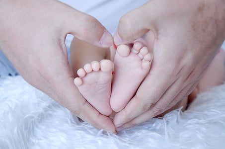 person making hand heart with baby's feet