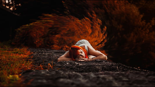 red-dyed haired woman in white dress lying on ground