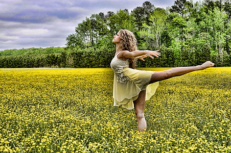 woman dancing on yellow rapeseed flower field during daytime