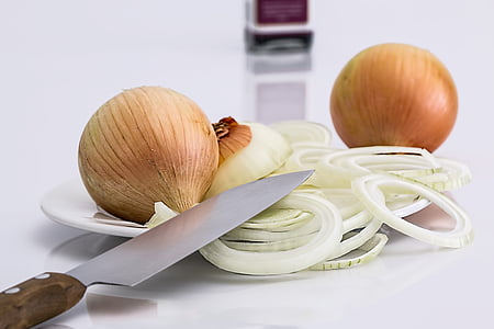 sliced onions on saucer near knife