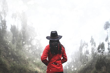 woman in red jacket standing between trees