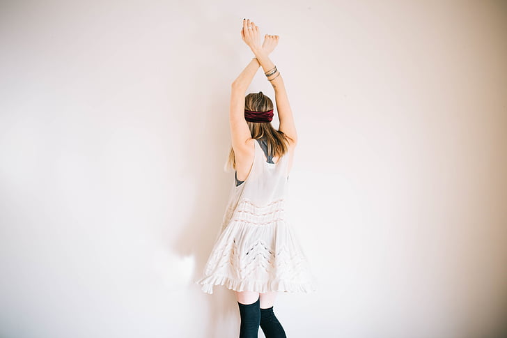 woman wearing white sleeveless dress lifting her both hands