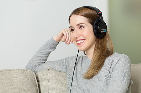 woman wearing black corded headphones while sitting on sofa