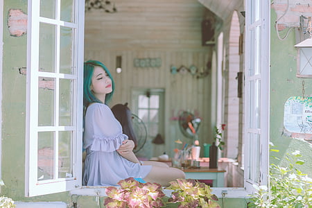 woman with green hair sitting on a window
