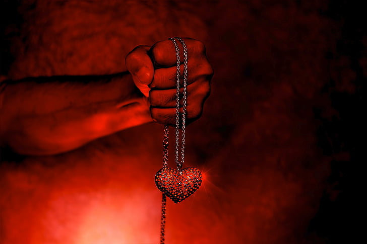 person holding red heart pendant necklace
