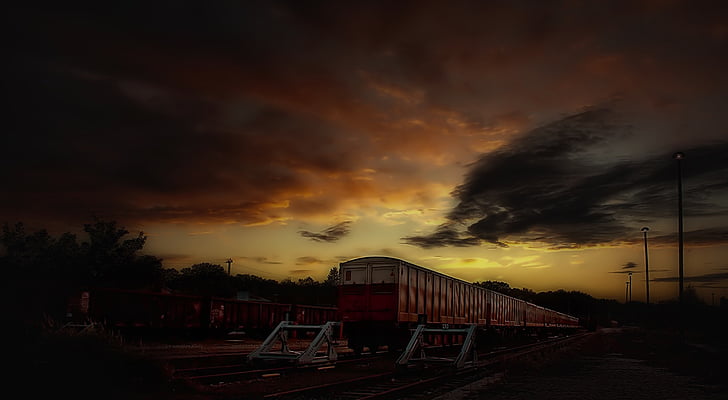 timelapse photo of train and silhouette trees