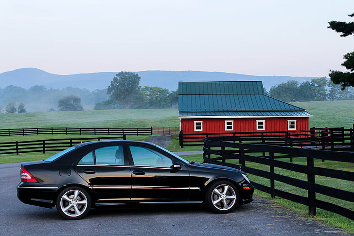 black sedan parked on concrete ground near red and black barn house