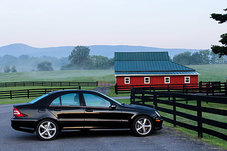 black sedan parked on concrete ground near red and black barn house