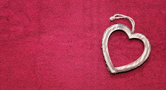 heart-shaped silver-colored pendant on top of red textile