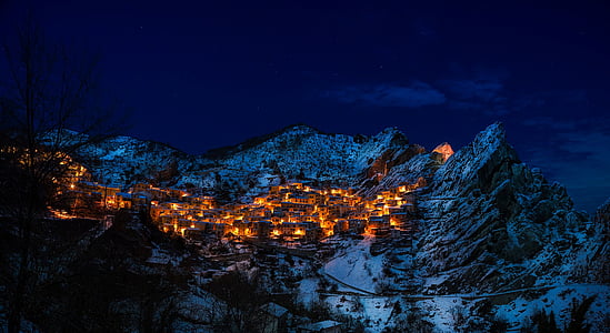 areal photo of turned on lights on village on snow filled mountain