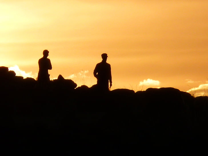 silhouette of two people on top of hill